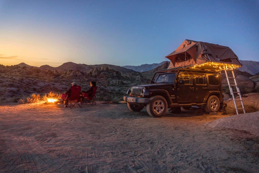 A jeep equipped with a roof top tent parked in the desert.