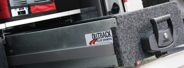 A close up of the back of a vehicle with cargo drawers and a sticker on it.