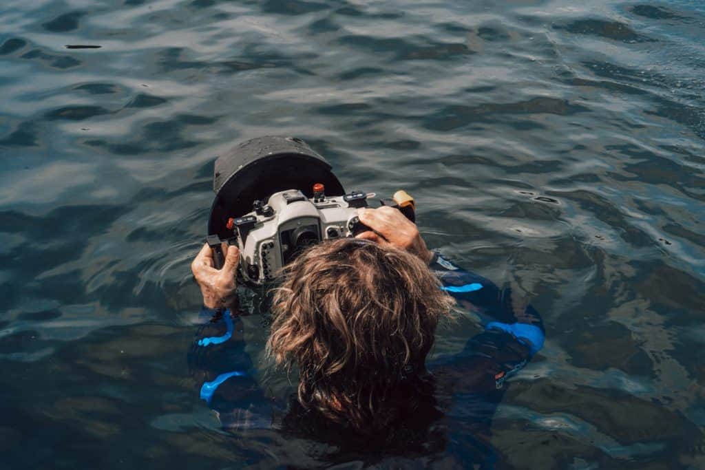 a man with an underwater camera in a body of water.