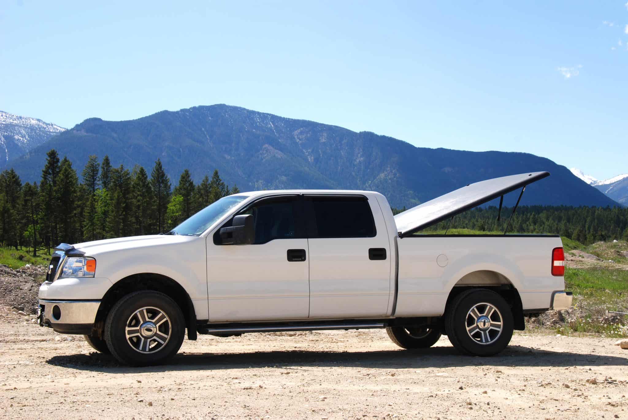 A pick up truck used for camping parked on a dirt road with essential camping accessories.