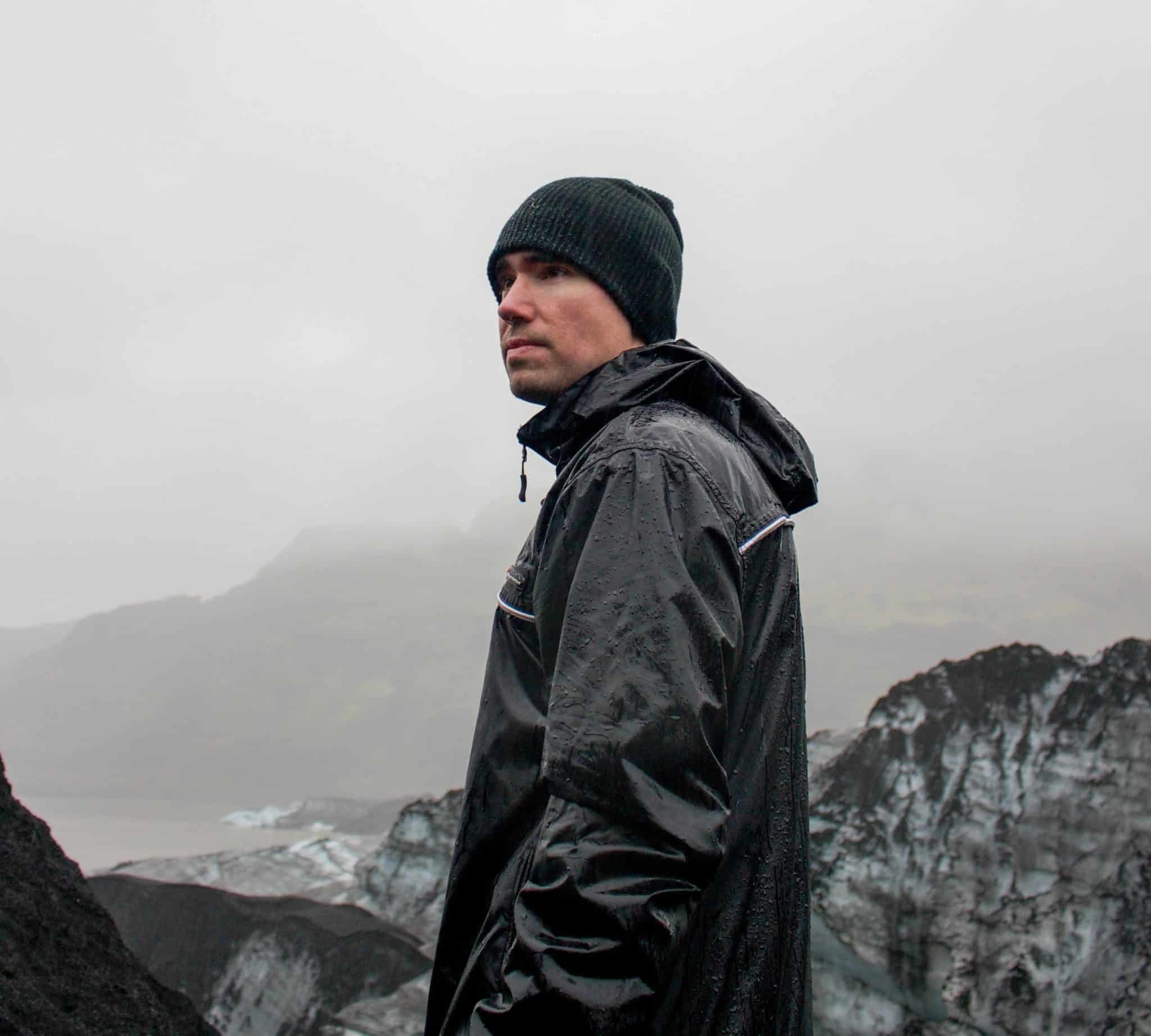 a man wearing essential camping accessories including a black jacket and a black hat.