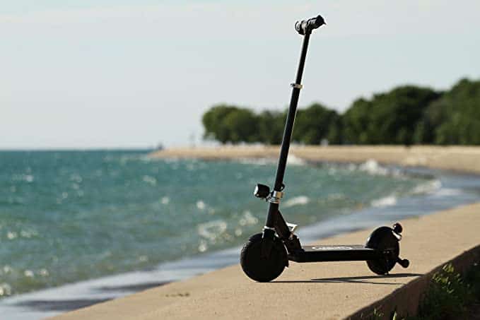 An e-scooter parked on the side of a beach.