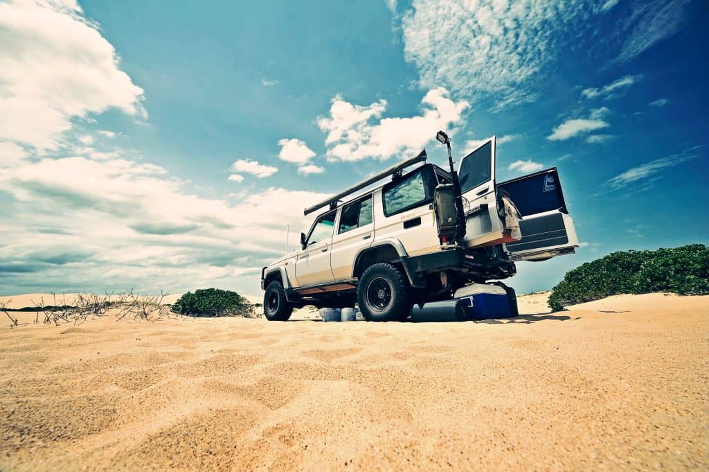 a white truck parked on top of a sandy beach.