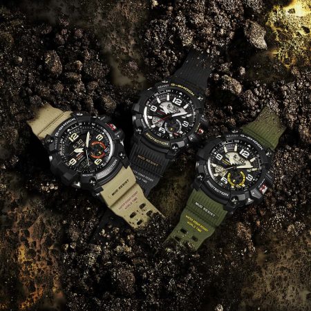 Three adventure watches laying on the ground in the dirt.